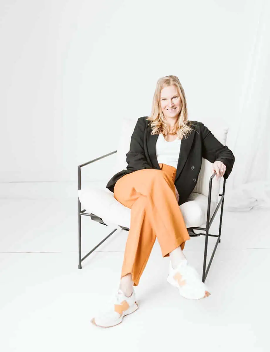 Photo of Dr. Joyce smiling relaxed in a modern chair, surrounded by an airy white background.