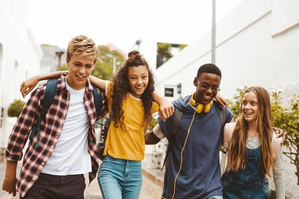 Photo of a pre-teen girl walking with her friends, smiling.