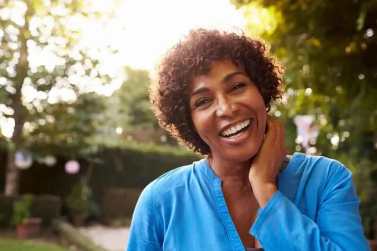 A woman outside in the sun smiling for the camera