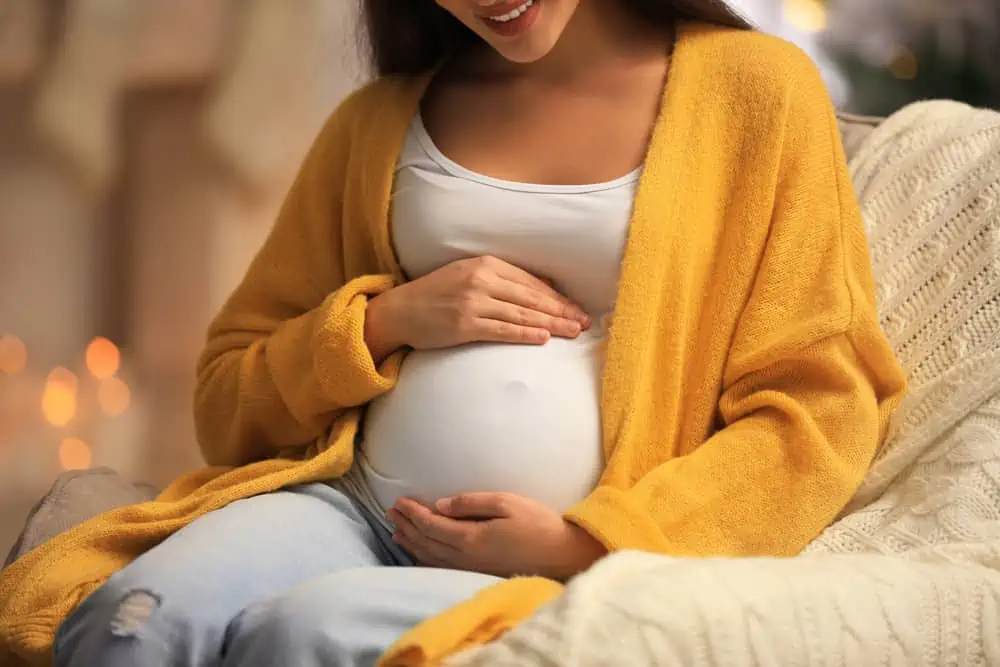 Photo of a smiling pregnant woman holding her belly